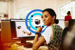 Mulher em frente a um computador, sorrindo, com ícones em tons de azul.