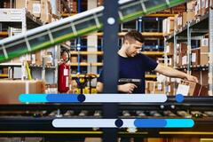 Profissional da área de logística confere produtos em estoque dentro de centro de distribuição, ilustrando vagas em logística operacionais