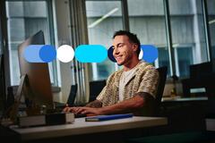 Homem vestido casualmente e utilizando computador em escritório, sorridente ao preencher habilidades profissionais no currículo.