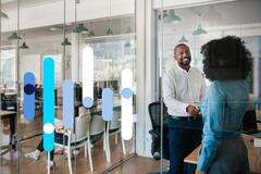 Homem e mulher apertam as mãos em escritório de RH em empresa, após entrevista de emprego.