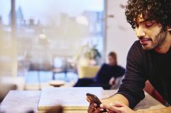 Man leaning on the kitchen counter top, looking at his phone.