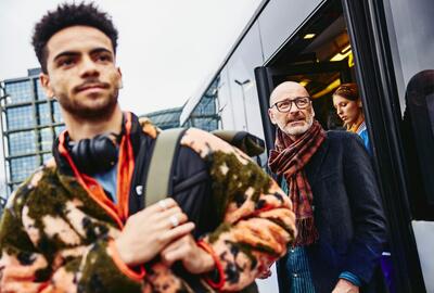 young man and older gentleman smiling walking out of train station