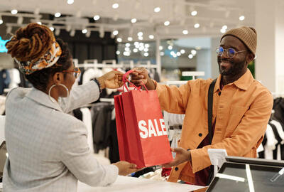 profissional auxiliando cliente com compras, representando as vagas para Black Friday