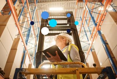 Mulher vestindo equipamentos de proteção e utilizando tecnologia para trabalhar em logística.