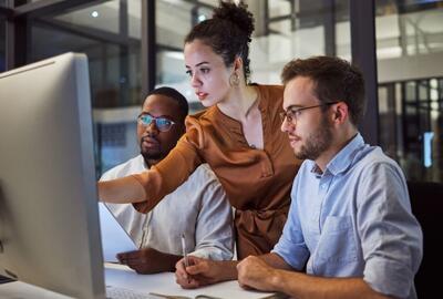 Três profissionais de RH pesquisando onde e como contratar profissional de TI hoje.