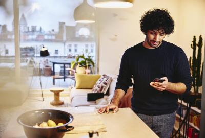 Man standing next to the kitchen counter top, looking at his phone.