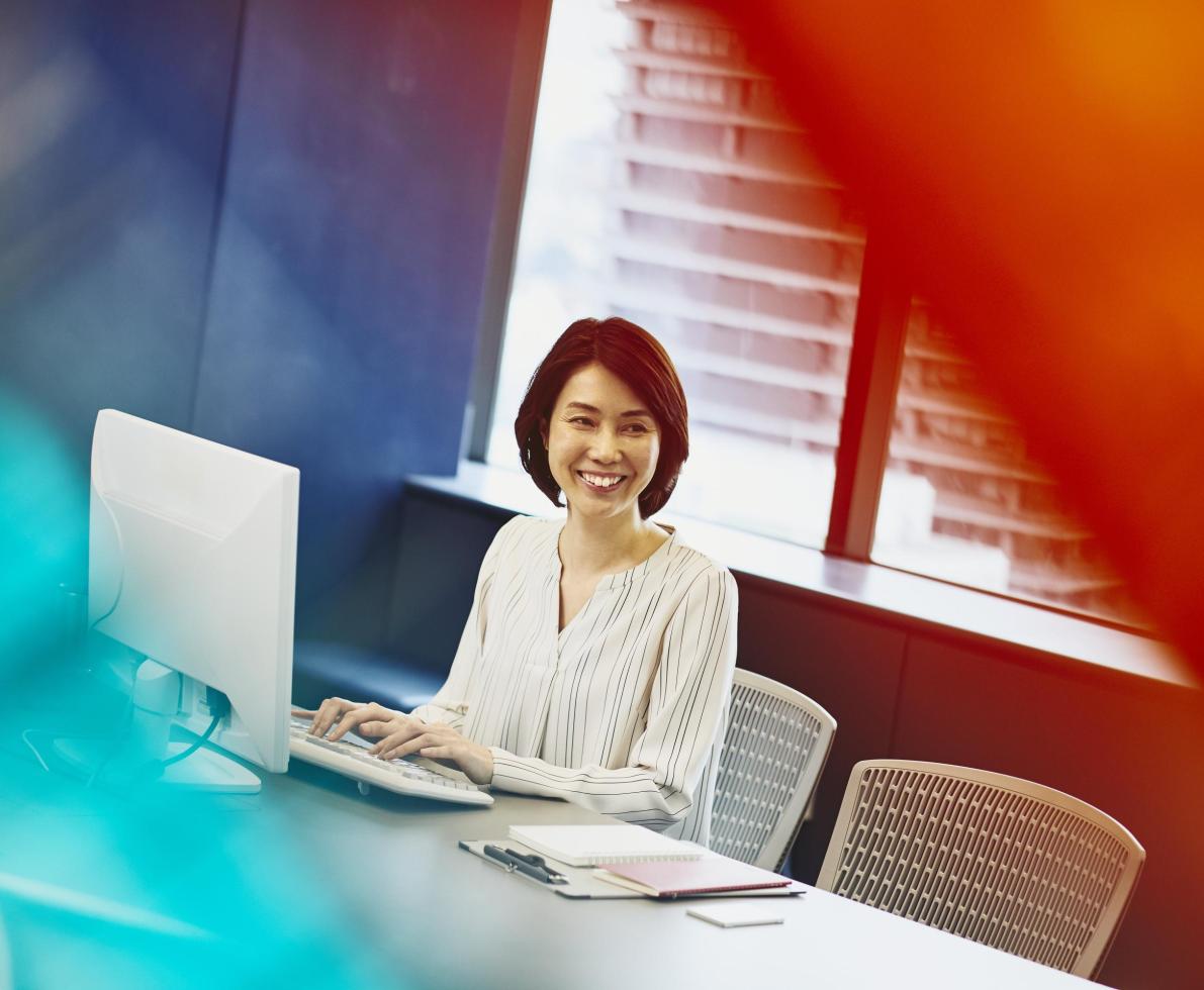 asian woman smiling while working on a computer
