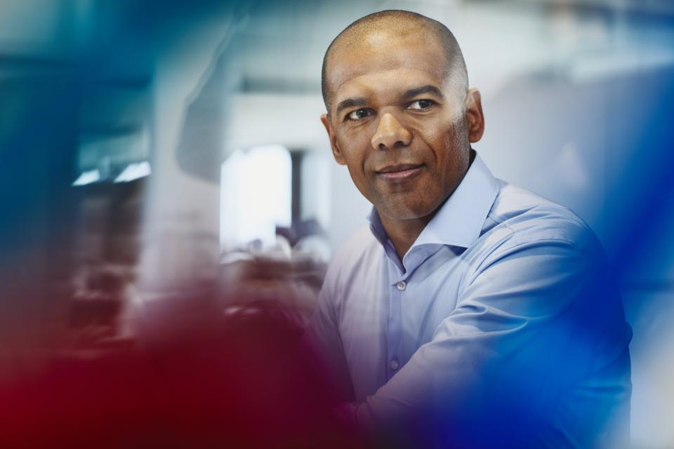 Man in shirt in an office. Primary colors: red and blue.