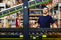 Smiling male standing behind a conveyor belt